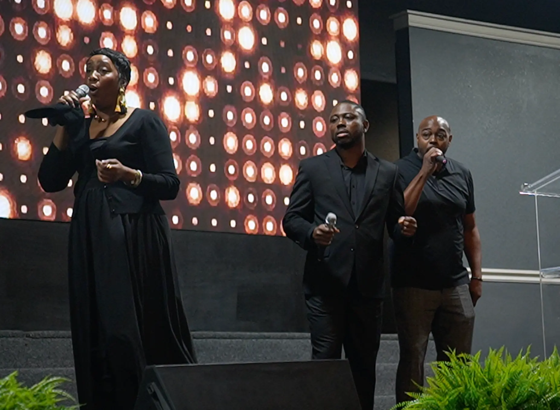Worship team leading songs of praise on stage with stage lights behind them