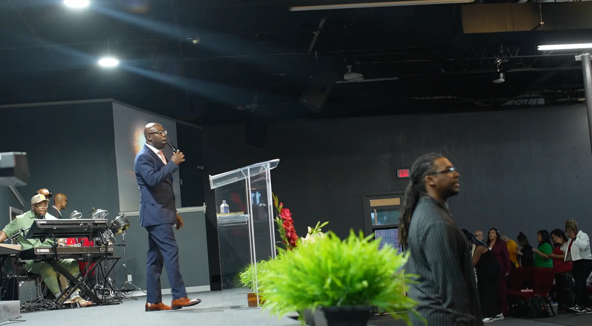 Apostle Frank Manu ministering on stage with the worship band during service